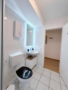 a white bathroom with a black toilet and a sink at FeWo Lindenallee Modern & Ruhig in Nordhorn
