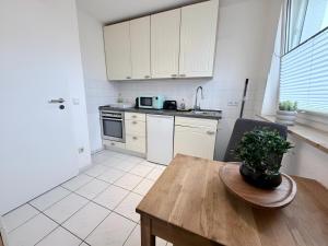 a kitchen with white cabinets and a wooden table at FeWo Lindenallee Modern & Ruhig in Nordhorn +9 photos