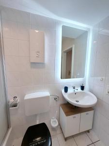a white bathroom with a sink and a mirror at FeWo Lindenallee Modern & Ruhig in Nordhorn