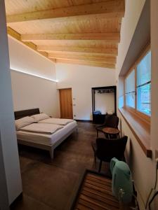 a bedroom with a bed and a chair in a room at B&B Le Origini in Ledro