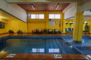 ein Schwimmbad mit Stühlen und Tischen in einem Gebäude in der Unterkunft Portimão Center Hotel by Umbral in Portimão