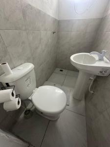 a bathroom with a white toilet and a sink at NOVO Ap Econômico em Paranaguá Completo com WiFi e Estacionamento Rotativo in Paranaguá