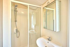 a bathroom with a shower and a sink and a mirror at Cedar Lodge With Hot Tub in Pocklington +15 photos
