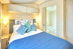 a bedroom with a large bed with blue pillows at Cedar Lodge With Hot Tub in Pocklington