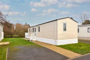 a large white building with a porch and grass at Cedar Lodge With Hot Tub in Pocklington
