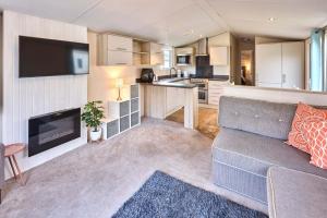 a living room with a couch and a kitchen at Cedar Lodge With Hot Tub in Pocklington