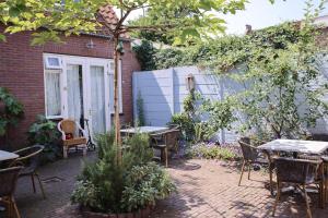 a patio with tables and chairs in a garden at Hotel Steeds aan Zee in Katwijk aan Zee