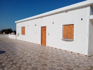 a white building with a door and a tile floor at Marwan Farmhouse Rooftop Apartment in Faraj Māḑī