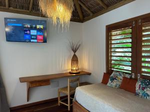 a bedroom with a bed and a desk and a tv at Tiki Pool's Bungalows in Fortim