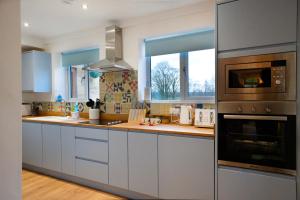 a kitchen with white cabinets and a stove top oven at Athelas, self catering cottage in Whitby +22 photos