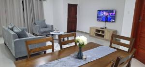 a living room with a table and chairs and a tv at Witu Apartments in Lusaka