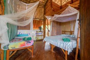 a bedroom with two beds and mosquito nets at Raízes Eco Hostel in Barra Grande
