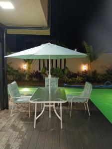 a table and chairs with an umbrella next to a pool at Luxury Villa by Andres in San Juan