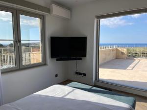a bedroom with a flat screen tv and a large window at Villa Lippia in Misraħ Miel