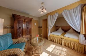 a bedroom with a bed and a couch and a chair at Hotel & Restaurant Landhaus Hönow in Hönow