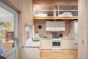 a small kitchen with white cabinets and a stove at M402-Vaeggerlose-Stolt-Henriksvej-93 in Bøtø By +11 photos