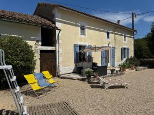 two chairs and an umbrella in front of a house at Les volets bleus in Saint-Saviol