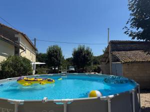 a large swimming pool with inflatables in a yard at Les volets bleus in Saint-Saviol