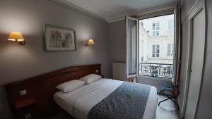 a bedroom with a bed and a large window at Hotel Richmond Gare du Nord in Paris
