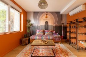 a living room with orange walls and a bed and a table at Air Nomad • Marrakech in Valenciennes