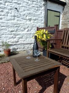 a wooden table with two wine glasses and a bottle at Middlehope Cottage in Westgate