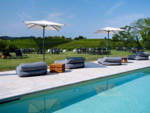 a group of lounge chairs and umbrellas next to a pool at Bosco Romagno in Cividale del Friuli