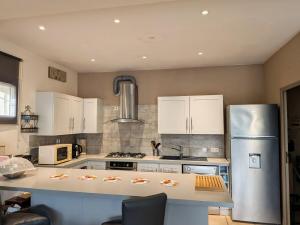 a kitchen with white cabinets and a stainless steel refrigerator at Quiet house, sun and pool in Le Thor