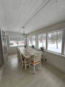 a dining room with a table and chairs and windows at Mormors hus in Jörlanda