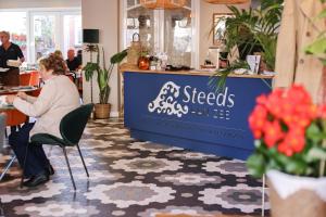 a woman sitting in a chair in a restaurant at Hotel Steeds aan Zee in Katwijk aan Zee