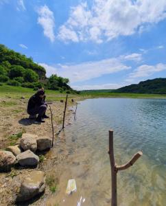 a person squatting next to a body of water at Arashenda nest in Arashenda +6 photos