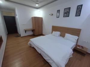 a bedroom with a white bed and a wooden floor at Prince Vatika in Alwar