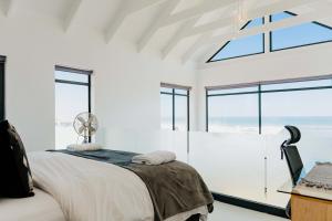 a bedroom with white walls and windows and a bed at Beyond The Beach in Yzerfontein