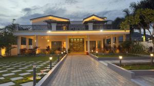 ein Haus mit einer gepflasterten Auffahrt davor in der Unterkunft Kurunchi Malar Resorts in Hosur + 14 Fotos