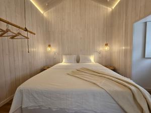 a bedroom with a large white bed with two lights at Grão de Areia - Mosteiros - 50m da praia - piscina privada in Mosteiros