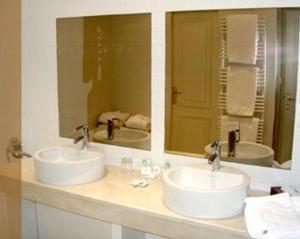 a bathroom with two sinks and two mirrors at Hôtel des Pyrénées in Saint-Jean-Pied-de-Port