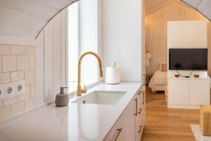 a white kitchen with a sink and a tv at Grão de Areia - Mosteiros - 50m da praia - piscina privada in Mosteiros +36 photos