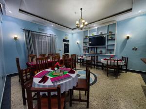 a dining room with tables and chairs and a tv at Kigongoni Gazella Hotel in Mto wa Mbu