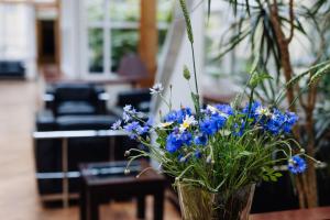 a vase filled with blue flowers on a table at Hestia Hotel Jugend in Riga +32 photos