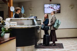 a man and a woman standing at a counter with luggage at Hestia Hotel Jugend in Riga