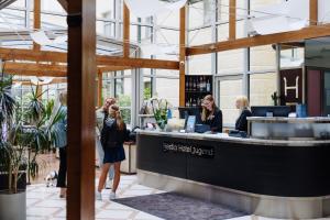 a group of people standing at a counter in a building at Hestia Hotel Jugend in Riga