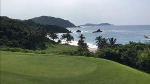 a golf course with the ocean in the background at Las Casitas de La Bahia Calechosa in Emiliano Zapata