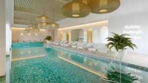 ein Pool in einem Hotel mit weißen Stühlen und einem Schwimmbecken in der Unterkunft Glory Resort in Baile Felix