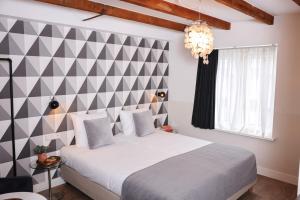 a bedroom with a white bed with a checkered wall at Hotel Steeds aan Zee in Katwijk aan Zee +226 photos