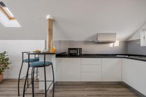 a kitchen with white cabinets and a counter with stools at Brito's Guest House - Monthly Rentals & Digital Nomads in Funchal