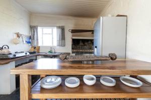 a kitchen with a wooden table with plates on it at Lumberjack Cottage at Blombosch Game Farm in Yzerfontein