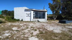 a small white house in the middle of a field at Lumberjack Cottage at Blombosch Game Farm in Yzerfontein