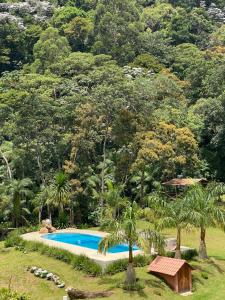 a swimming pool in front of a mountain with trees at Pousada Altitude 1200 in Fazendinha