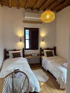 ein Schlafzimmer mit zwei Betten, einem Fenster und einem Ventilator in der Unterkunft Plagia Luxury Suites in Skyros