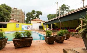 a swimming pool with potted plants next to a building at Admiral Hotel and Spa Kampala in Kampala