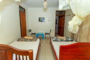 a room with two beds and a table and chairs at Admiral Hotel and Spa Kampala in Kampala